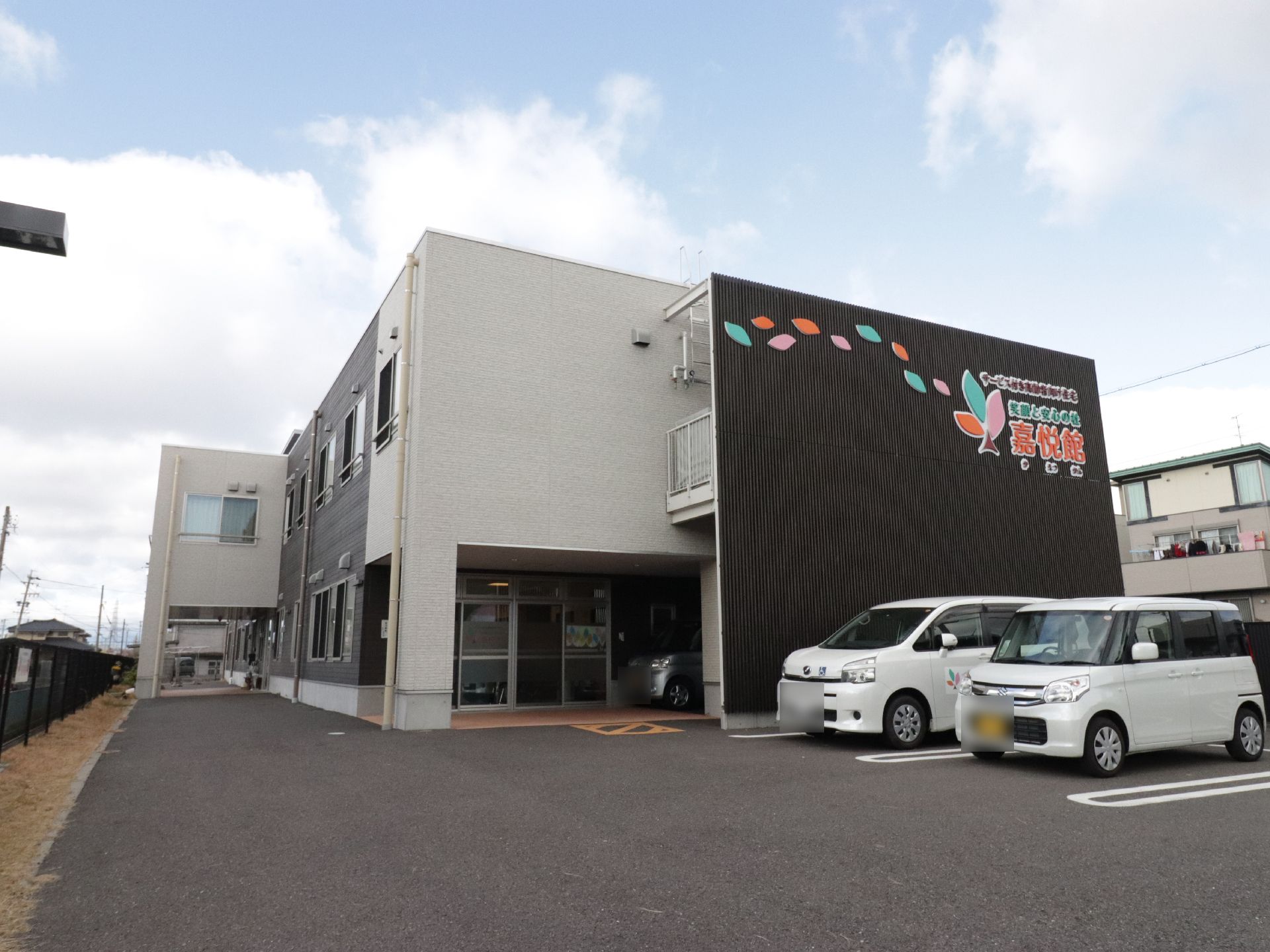 施設は２階建てである。外壁には大きくカラフルな文字で施設名が表示されている。建物の前には複数台停められる駐車場がある。