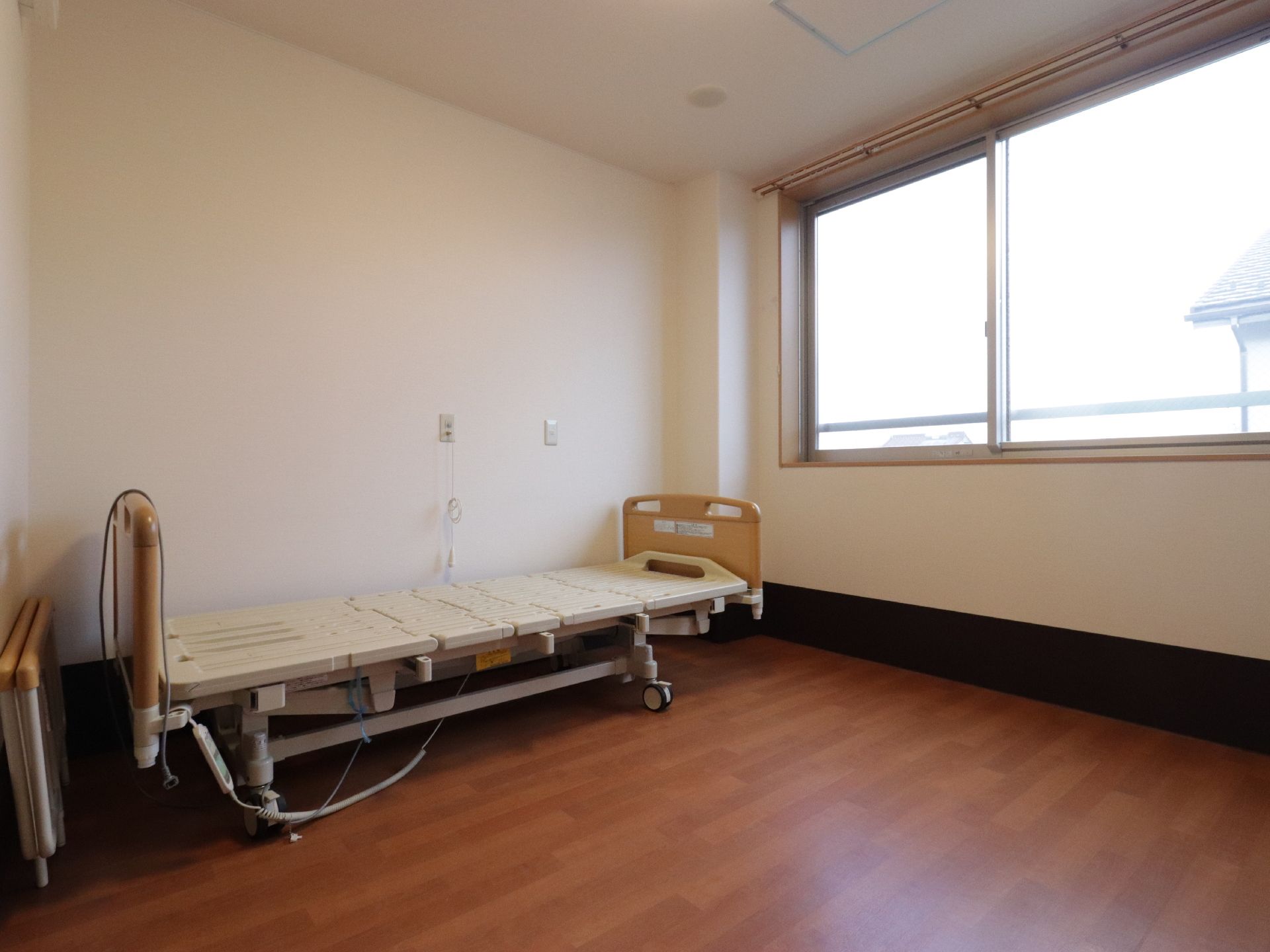 居室は大きな窓があり日当たりが良い。ベッドを置いてもゆとりのある広さがある。床はフローリングになっている。