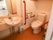 明るく清潔感のあるトイレには、洗面スペースと温水洗浄便座が完備されている。赤い手すりが目立って安全である。