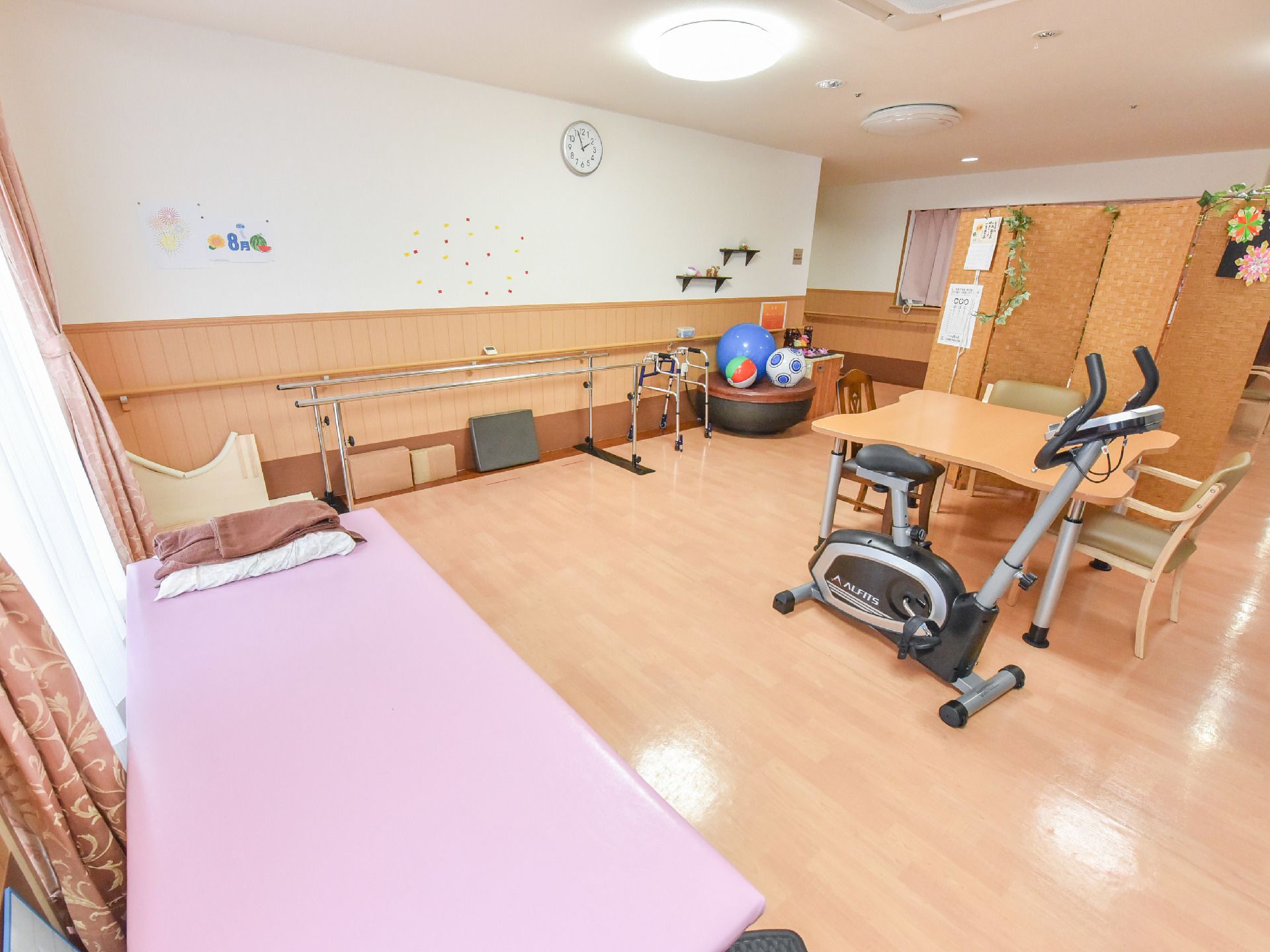 床はフローリングになっている。ゆったりとした空間にリハビリの道具が置かれている。窓からは光が差し、明るい。