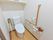 洋式トイレが設置され、まわりには手すりが取り付けられている。ナースコールもあり、安心。背面の壁の上部に棚を設置している。
