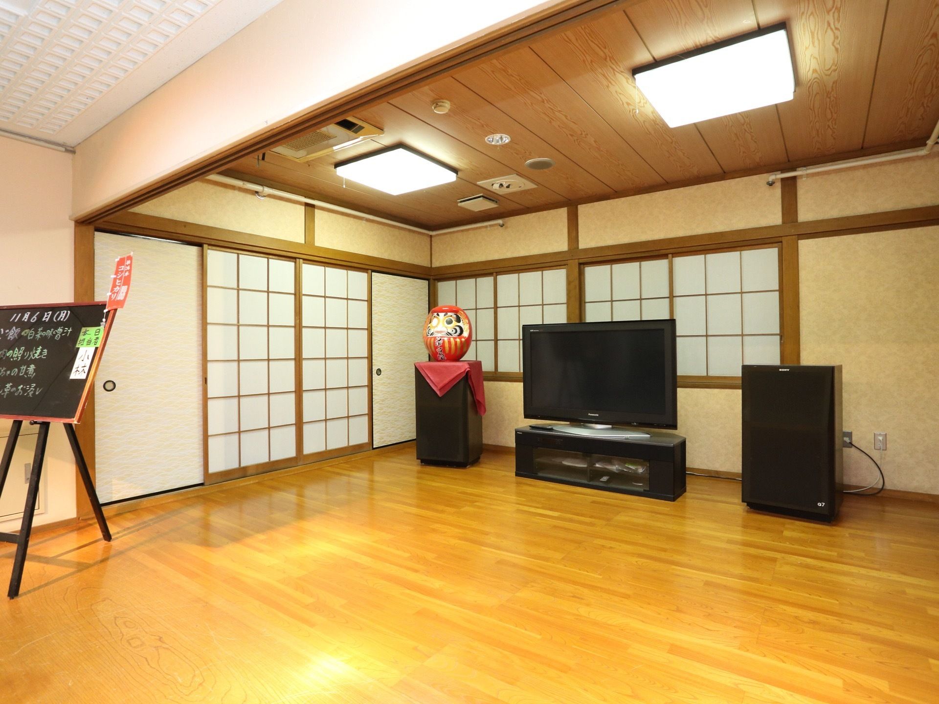大きなテレビが設置された広いスペースである。大きなだるまが飾られており、片目を入れた状態になっている。