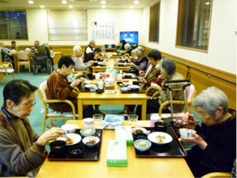 明るい木目調のテーブルで、配膳された料理を召し上がられる入居者様