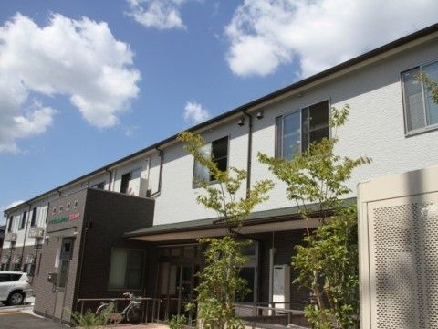 完備する植え込みの緑の背景に立地する２階建て施設の外観