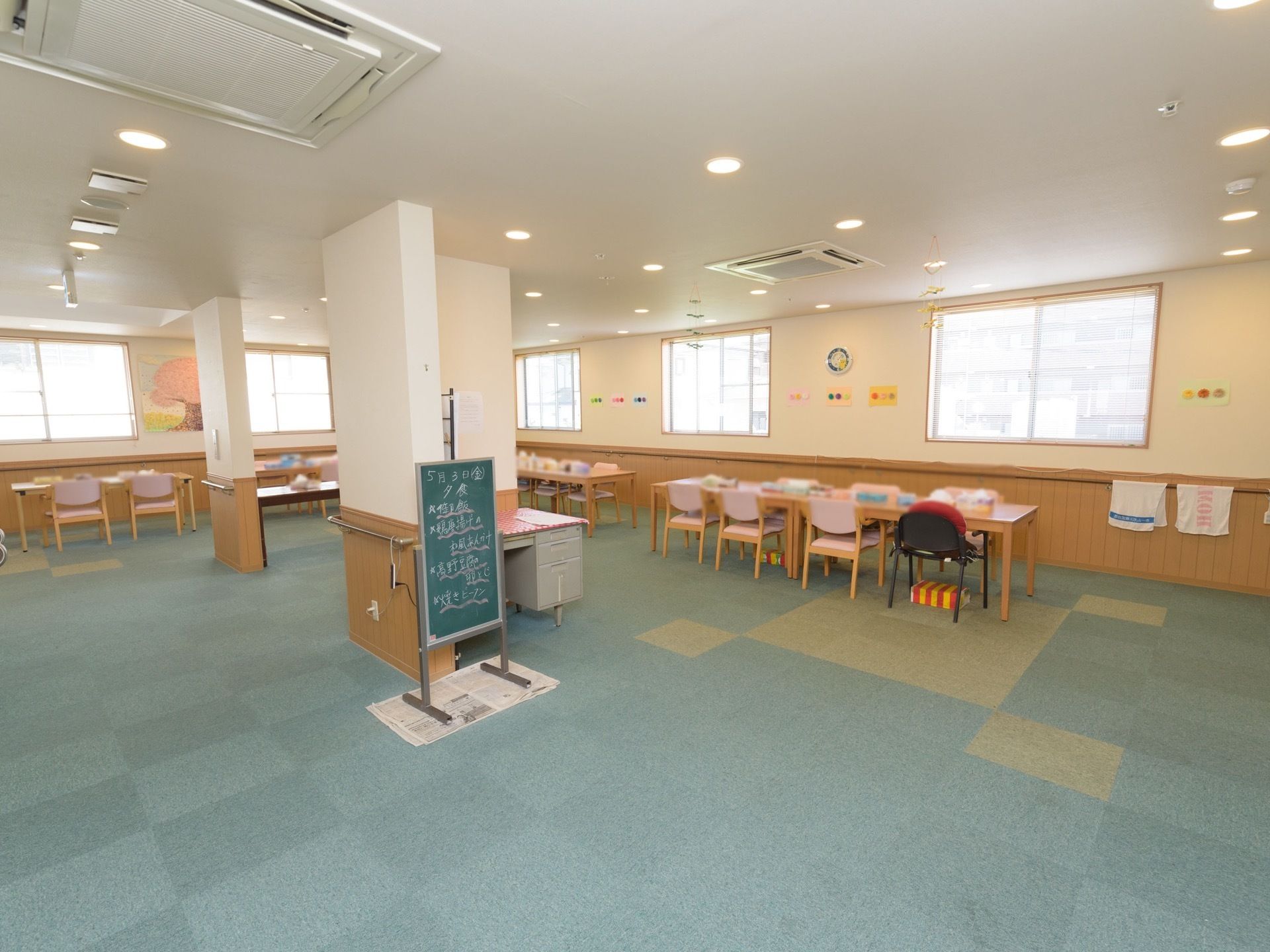 通路からよく見える位置に、看板型の黒板が置かれており、日付と献立が大きく書かれている。窓のそばに、テーブルや椅子が配置してある。