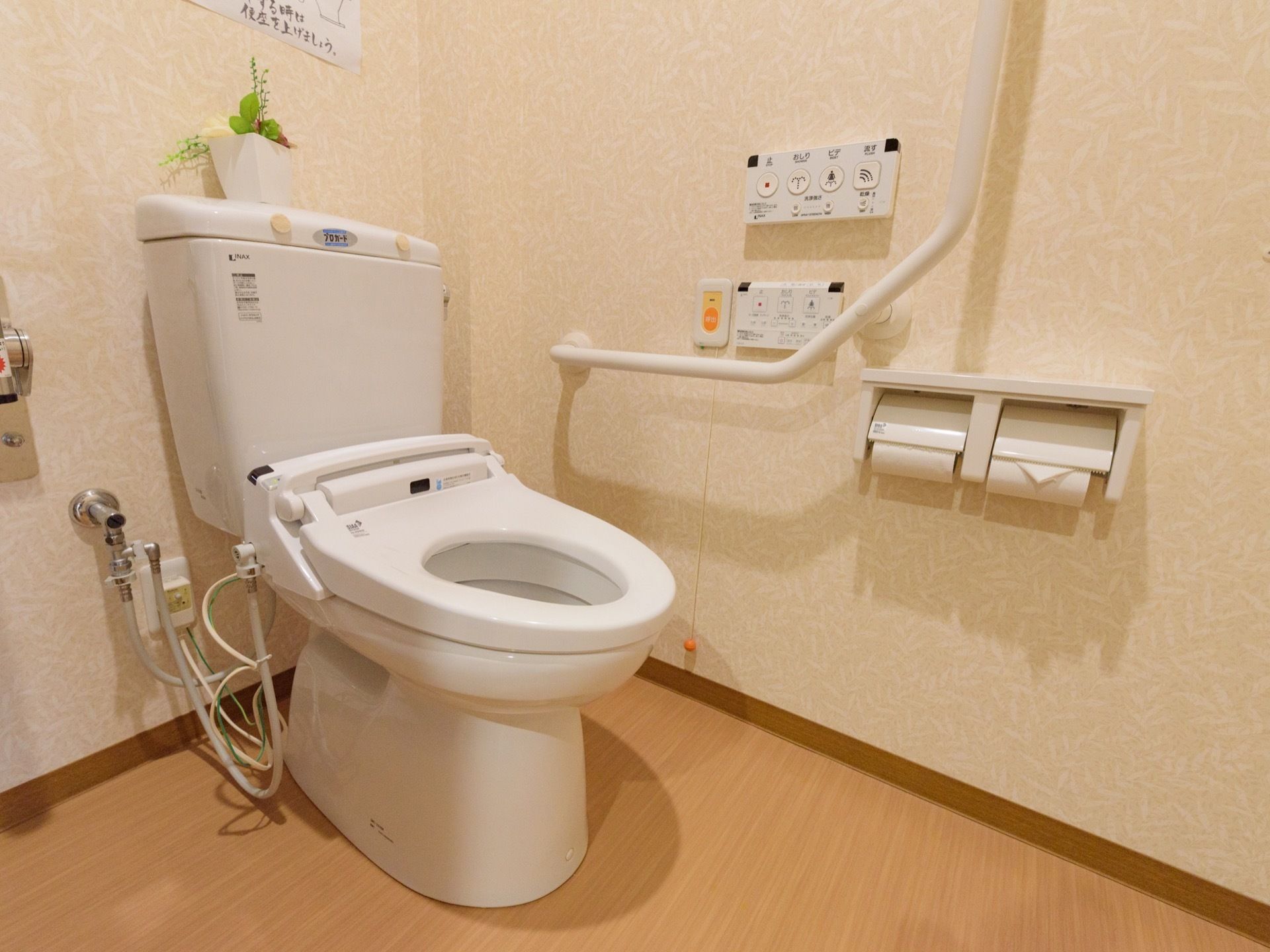 トイレの便座にはフタがついていない。壁には手すりが付いている。便座の周りには広くスペースがあり、車椅子をご利用の方でも利用しやすい。
