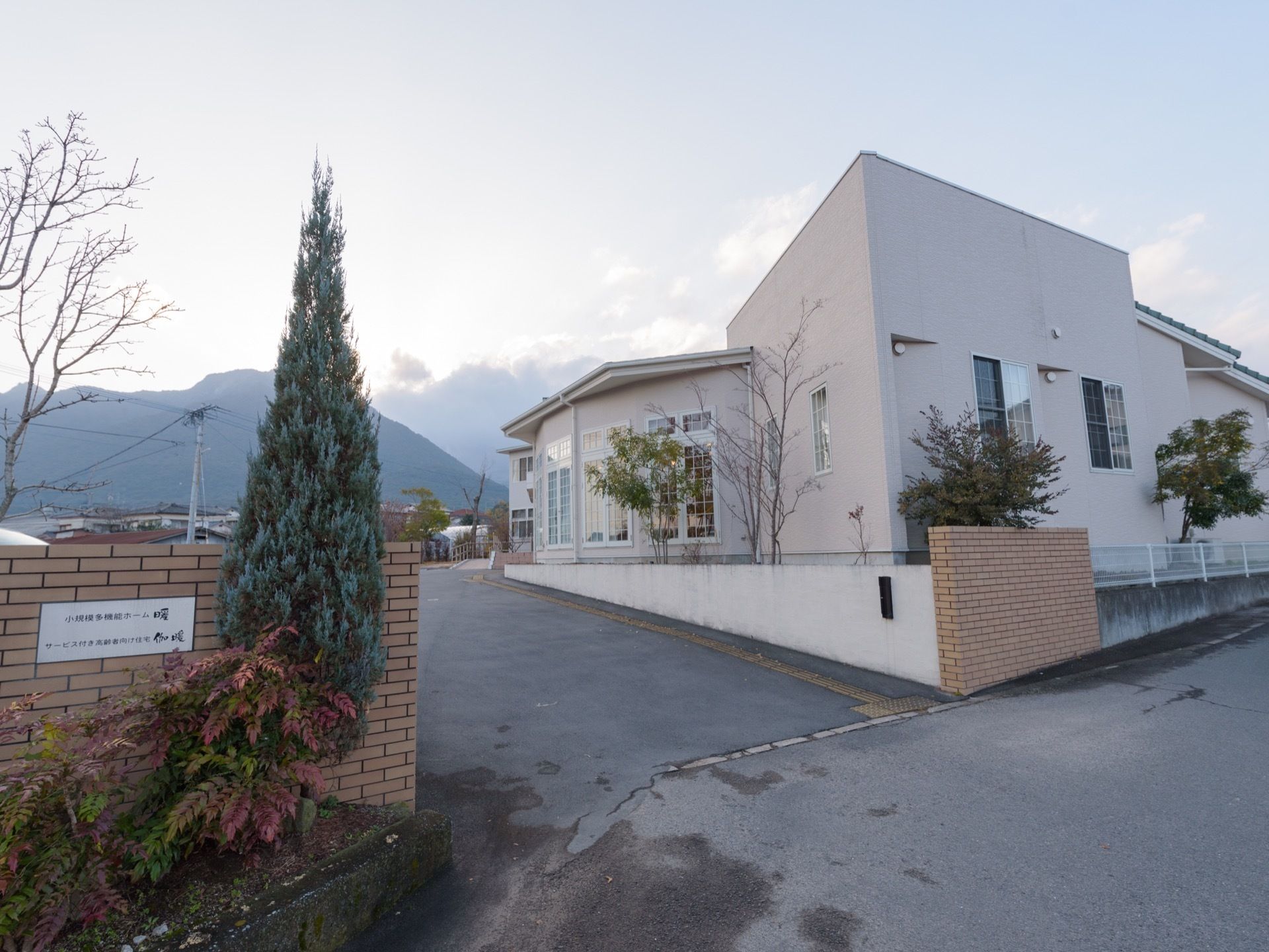 １階建ての洋風の建物で、門は広く車がスムーズに入ることができる。施設には窓がたくさん付いている。周りには植木がある。