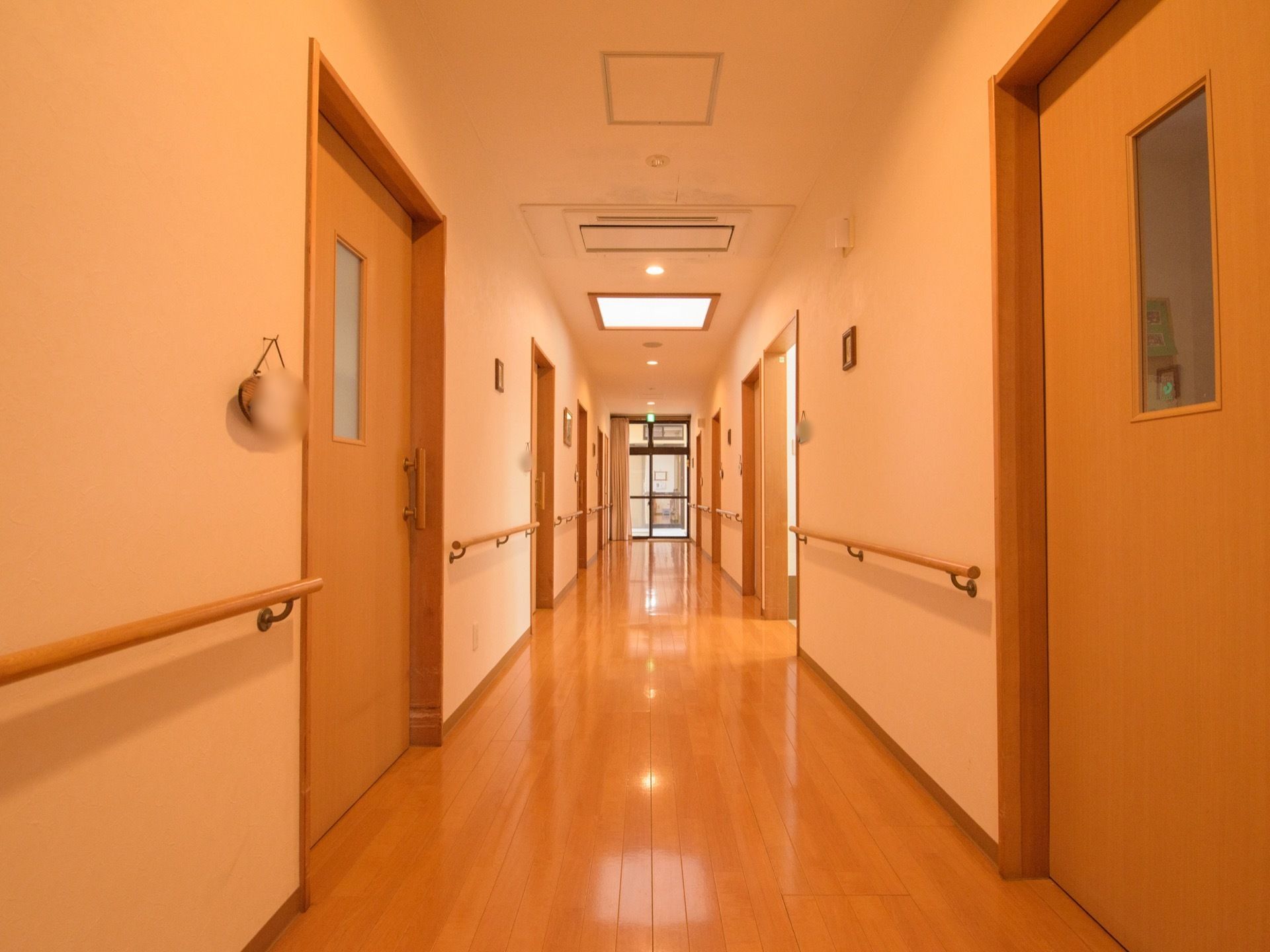 廊下は幅が広く、入居者様同士がすれ違う時にも余裕がある。手すりが設置されており、居室への扉にはすりガラスがついている。