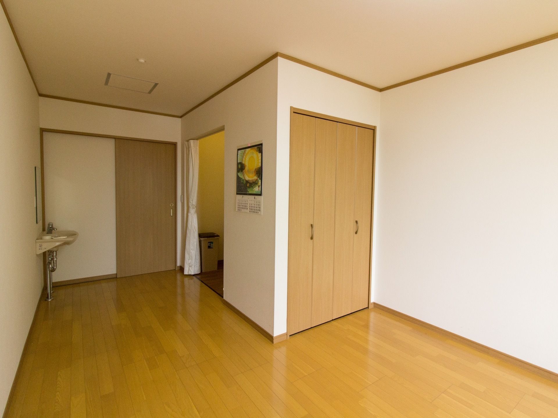 居室の入り口は、木目調のスライド式の扉である。入り口すぐに洗面台とトイレがあり、押入れが設置されている。