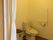 フローリングの床の広々としたトイレである。居室との仕切りは白色のカーテンであり、壁には手すりが設置されている。
