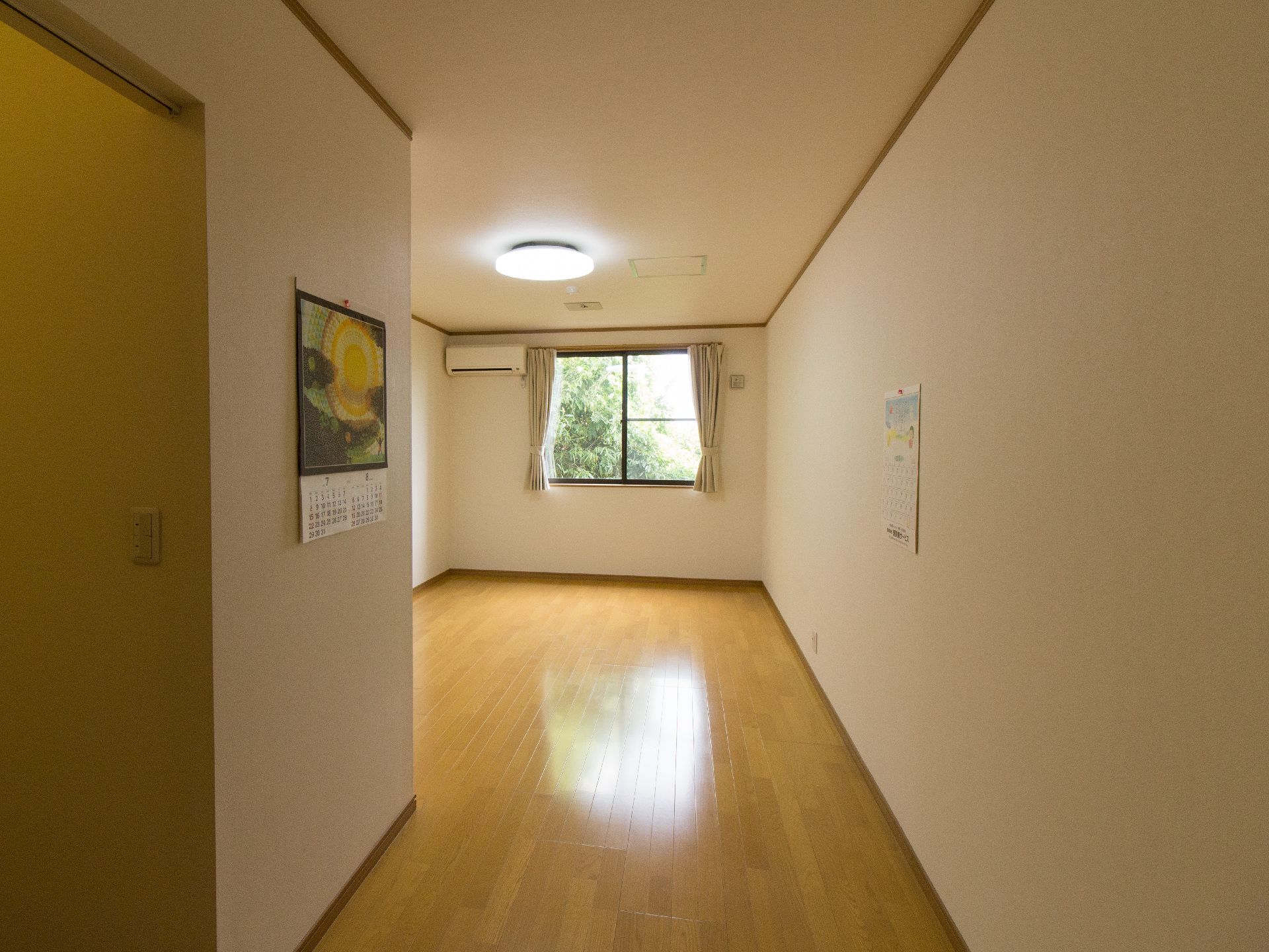 エアコンが設置され、窓から緑の景色が見えるご入居前の居室
