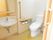 居室のトイレはウォシュレットの水洗トイレ。壁にはスイッチとペーパー、手すりがあり小型の洗面台と鏡も設置されている。