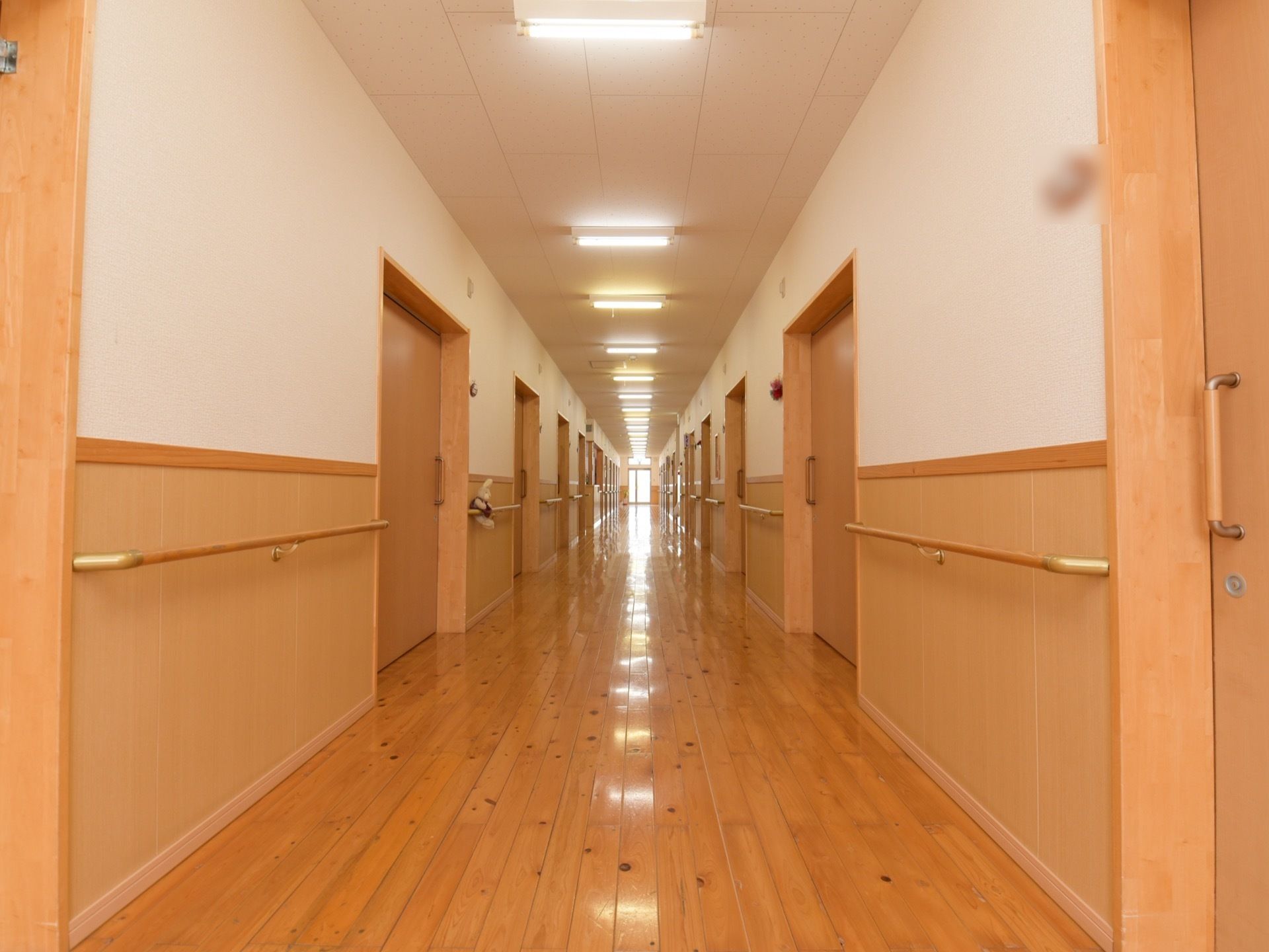 廊下がまっすぐ続いている。天井と壁の上半分は白色で、壁の下半分と床は木製である。両壁には手すりが設置されており、居室のドアが並んでいる。