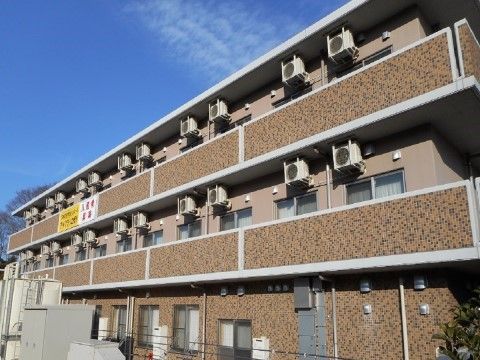 ベランダとエアコンを設置した小さなタイルデザインの外壁の施設外観