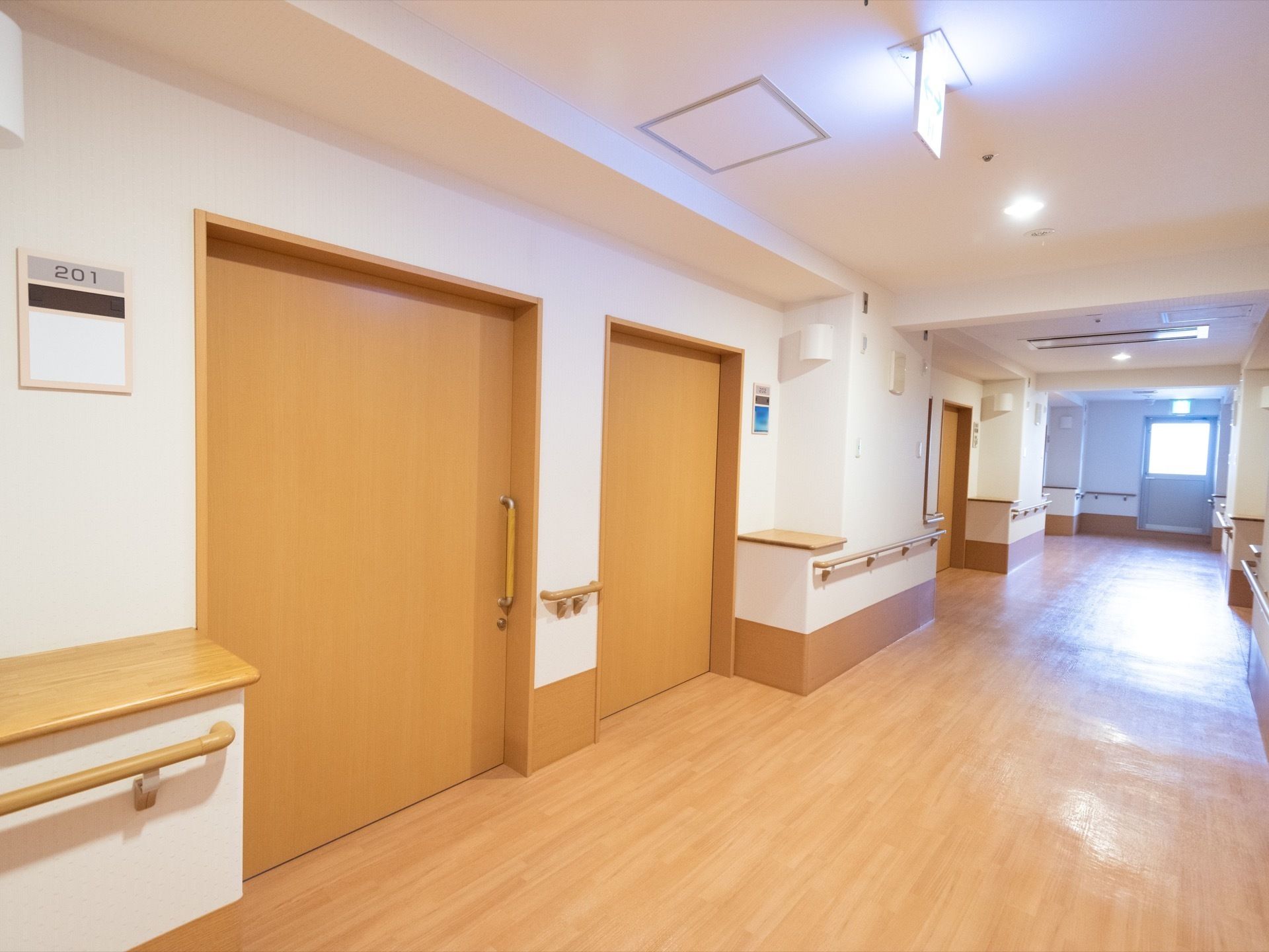 幅が広い廊下である。居室入口扉の横に、天板がついた四角の飾り棚が設置されている。つきあたりの扉は非常口になっている。