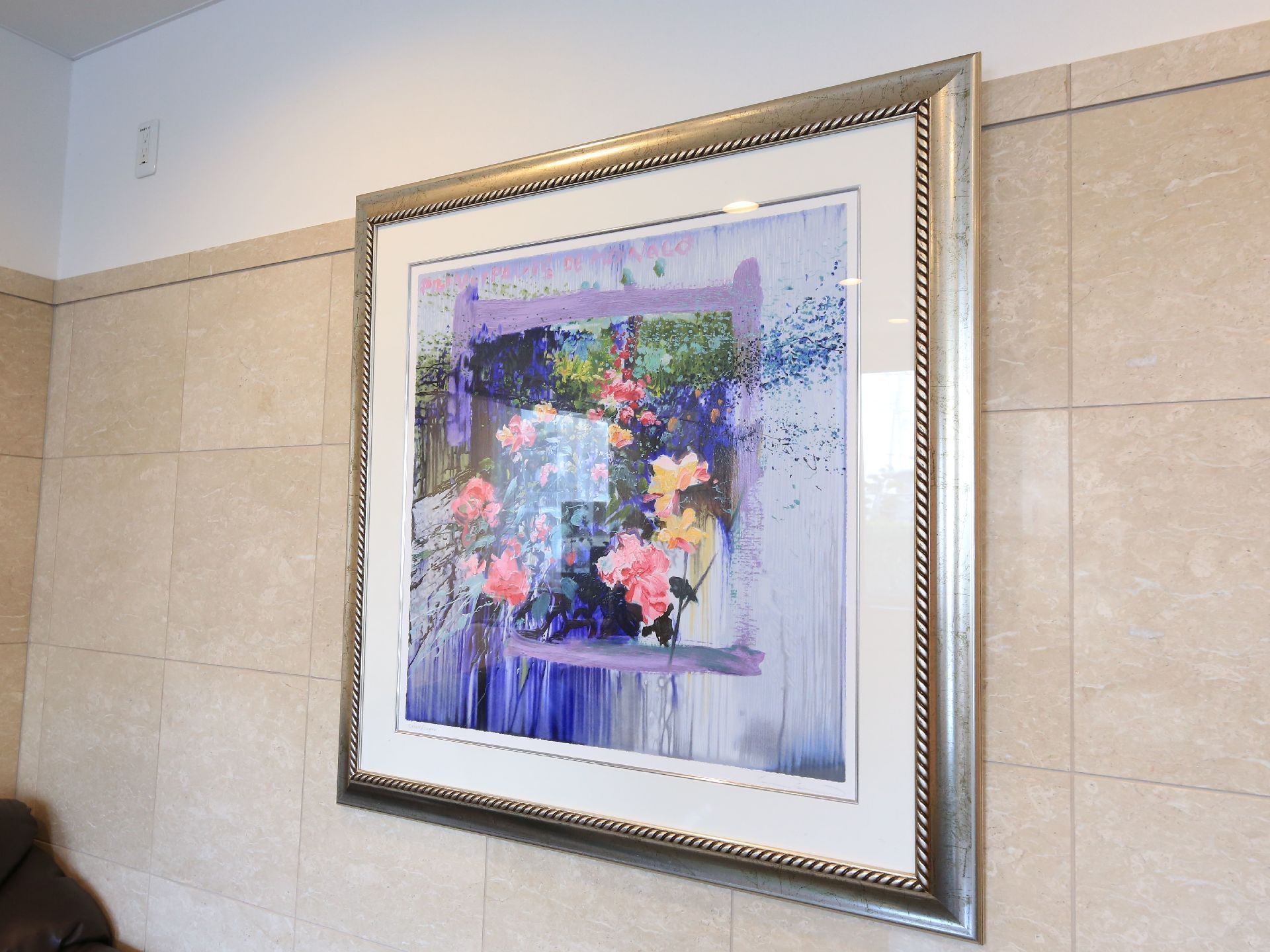 白とベージュのツートンカラーの壁に、額縁に入った花の絵画が飾られている。上部にコンセントタップが取りつけられている。