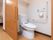 出入り口にスライド式の扉が採用されたトイレである。温水洗浄便座になっており、操作ボタンが壁に設置されている。