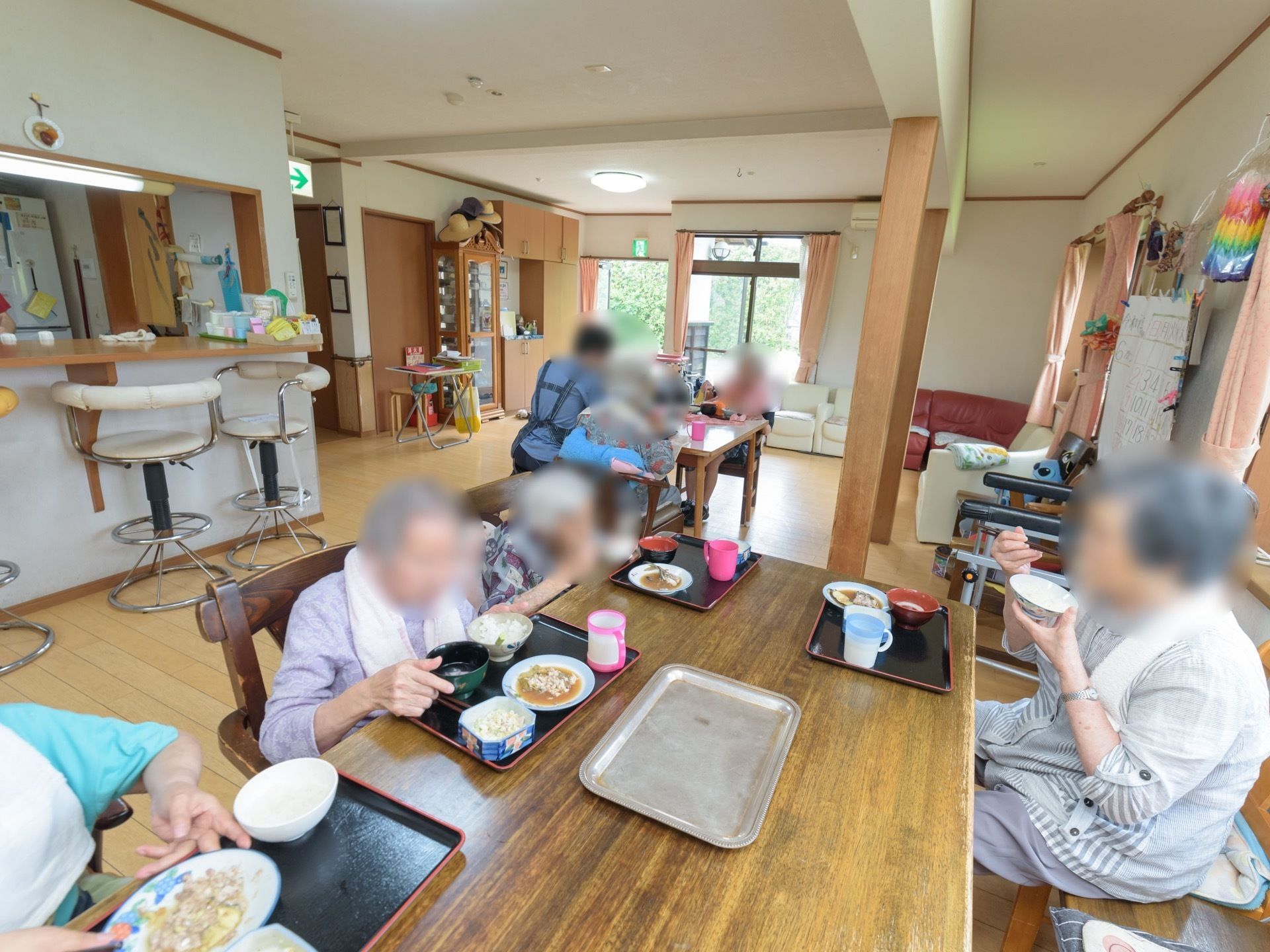食堂には窓が複数あり、自然の日差しが差し込んでいる。周囲の壁にはたくさんの掲示物や、折り紙の作品などが飾られている。