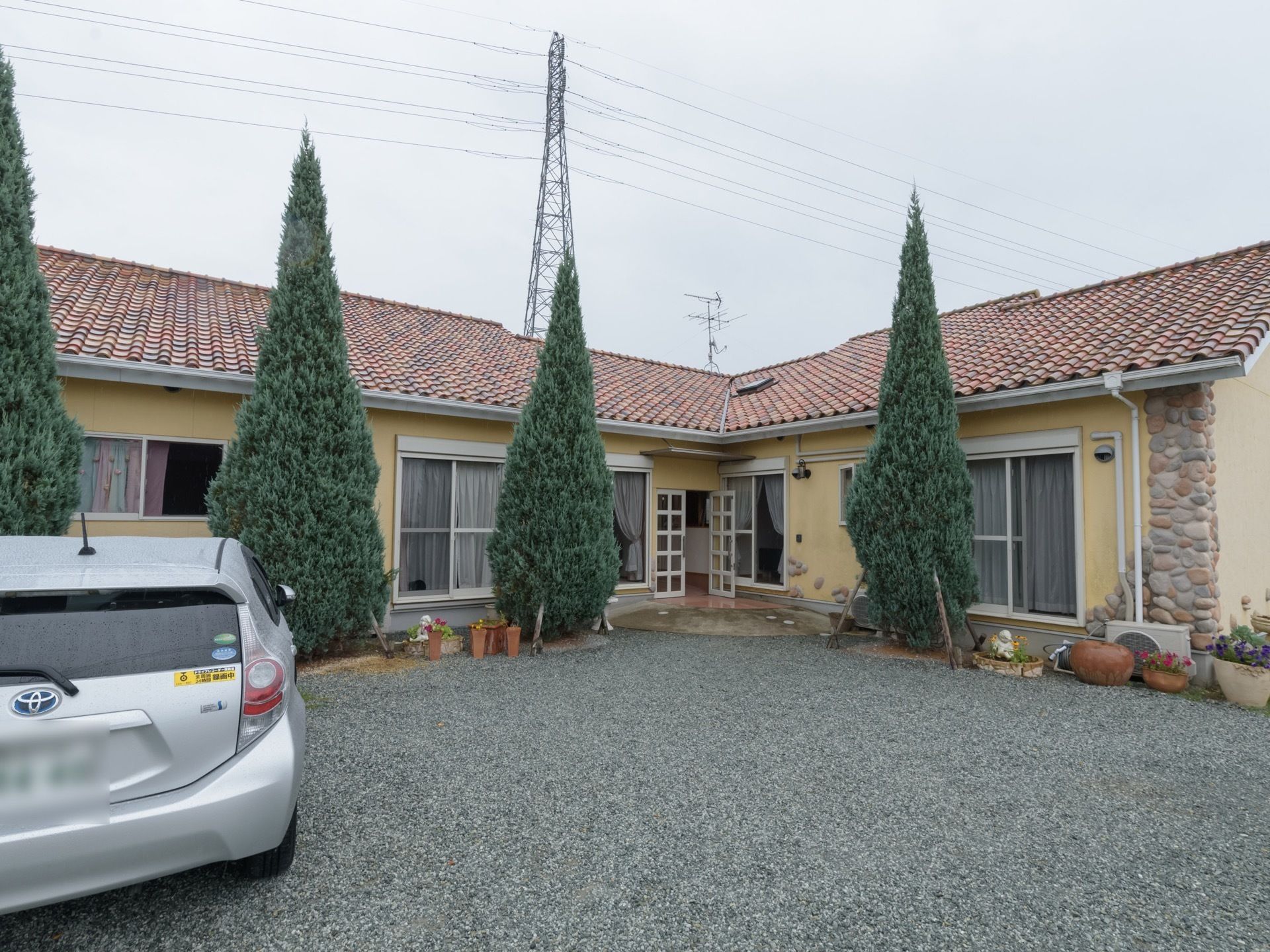淡い黄色の壁に、淡い茶色の屋根の洋風の平屋建て住宅風の外観である。ホームの周囲には、木が植えられ、駐車場があるのが見える。