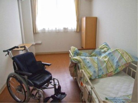 介護ベッドや車いすが置かれた日光が差し込む居室スペース