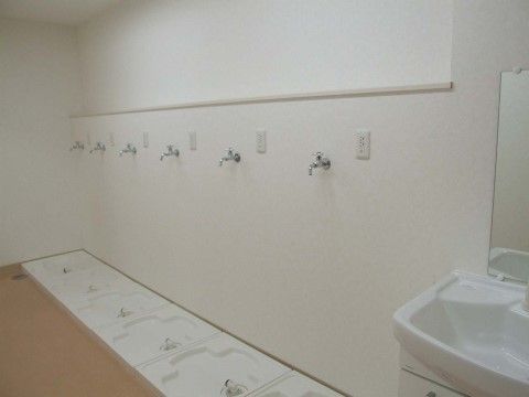 蛇口が６つ並んでいる。蛇口の下には洗濯機用の防水パンが敷かれている。洗濯機を並べて設置できる場所である。