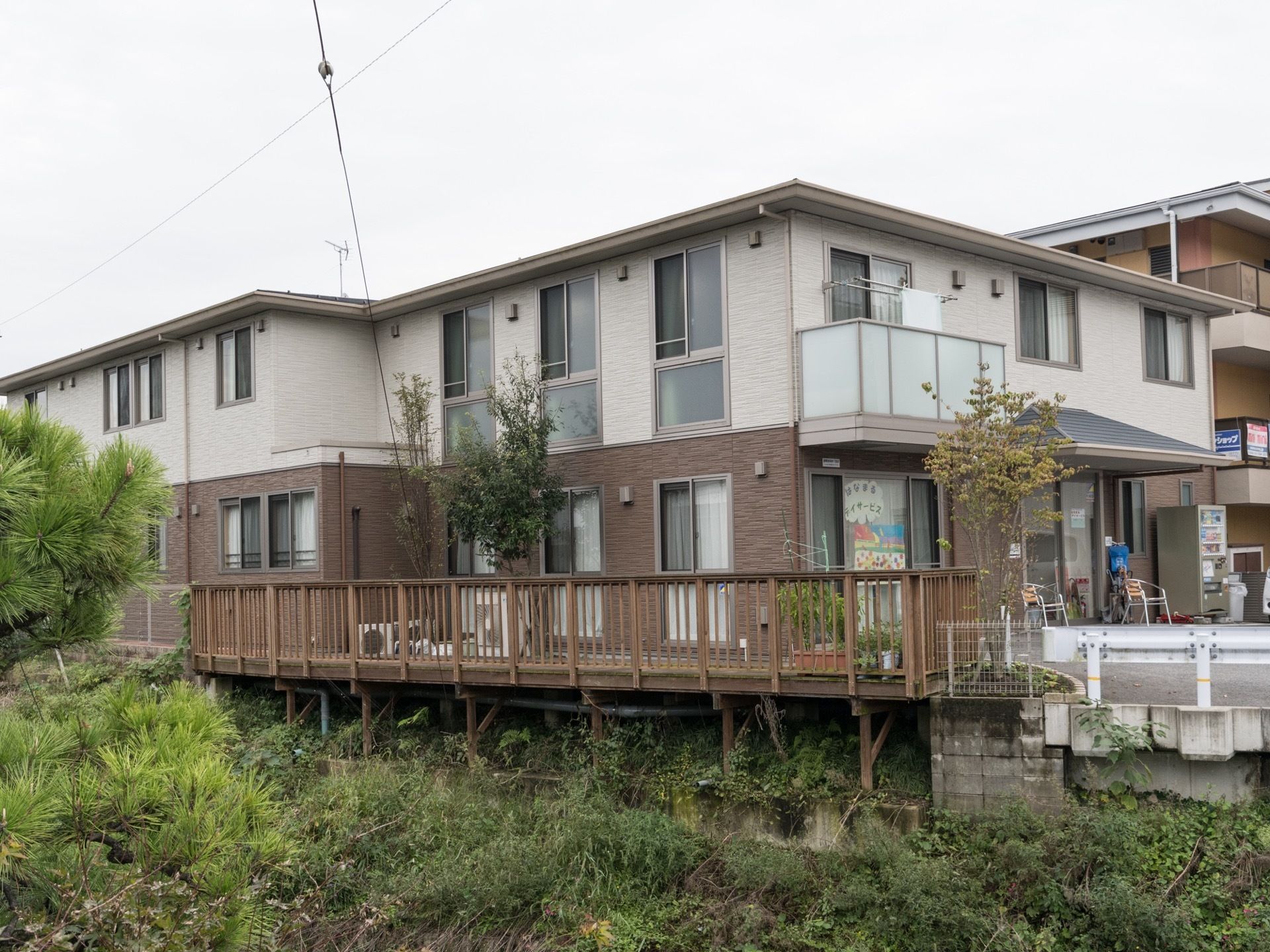 施設は小高い丘にあり、建物は２階建てになっている。また１階の野外部分には、広々としたデッキスペースを設置している。