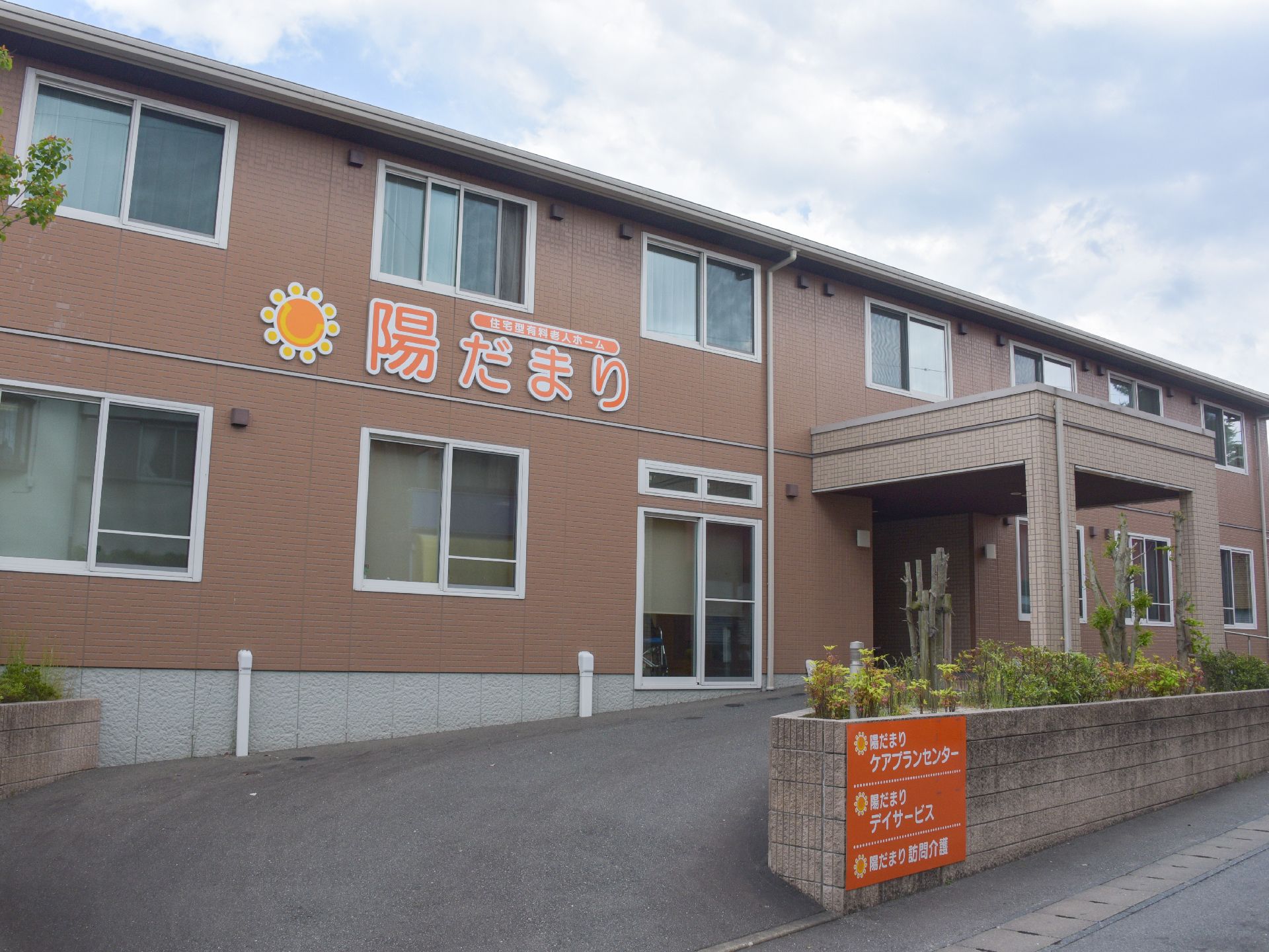 施設は茶色の2階建ての横長の建物になっている。壁には大きく施設名とロゴが貼り付けられている。玄関前まで車を乗り入れられるようになっている。