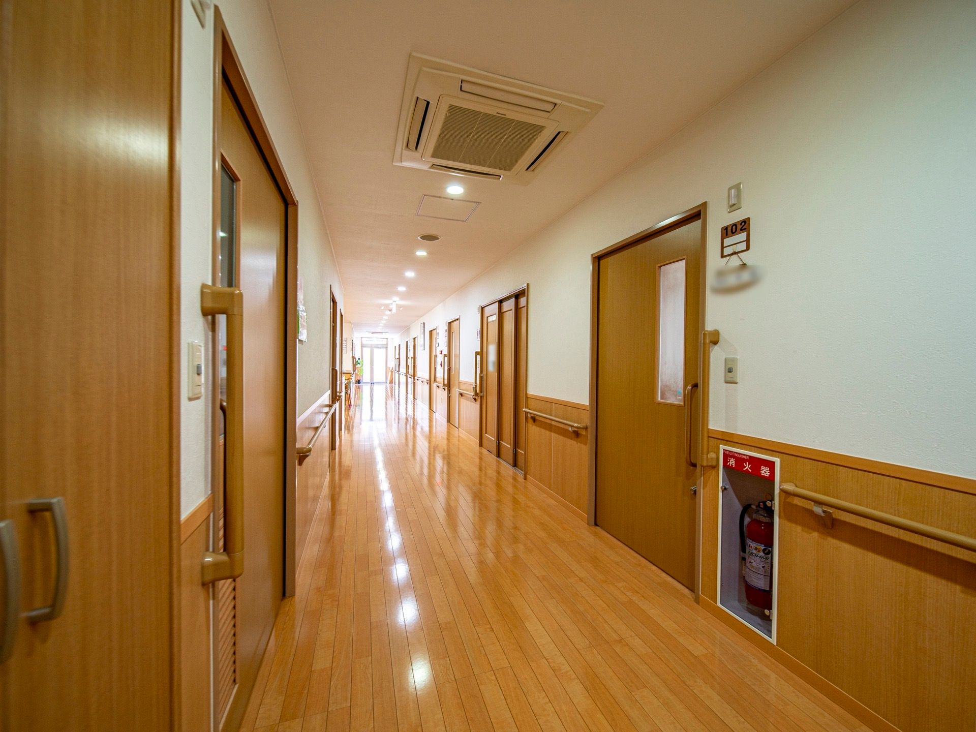 明るい廊下の壁全面に手すりが設置されている。消火器が設置されており、いざという時も落ち着いて対応することができる。