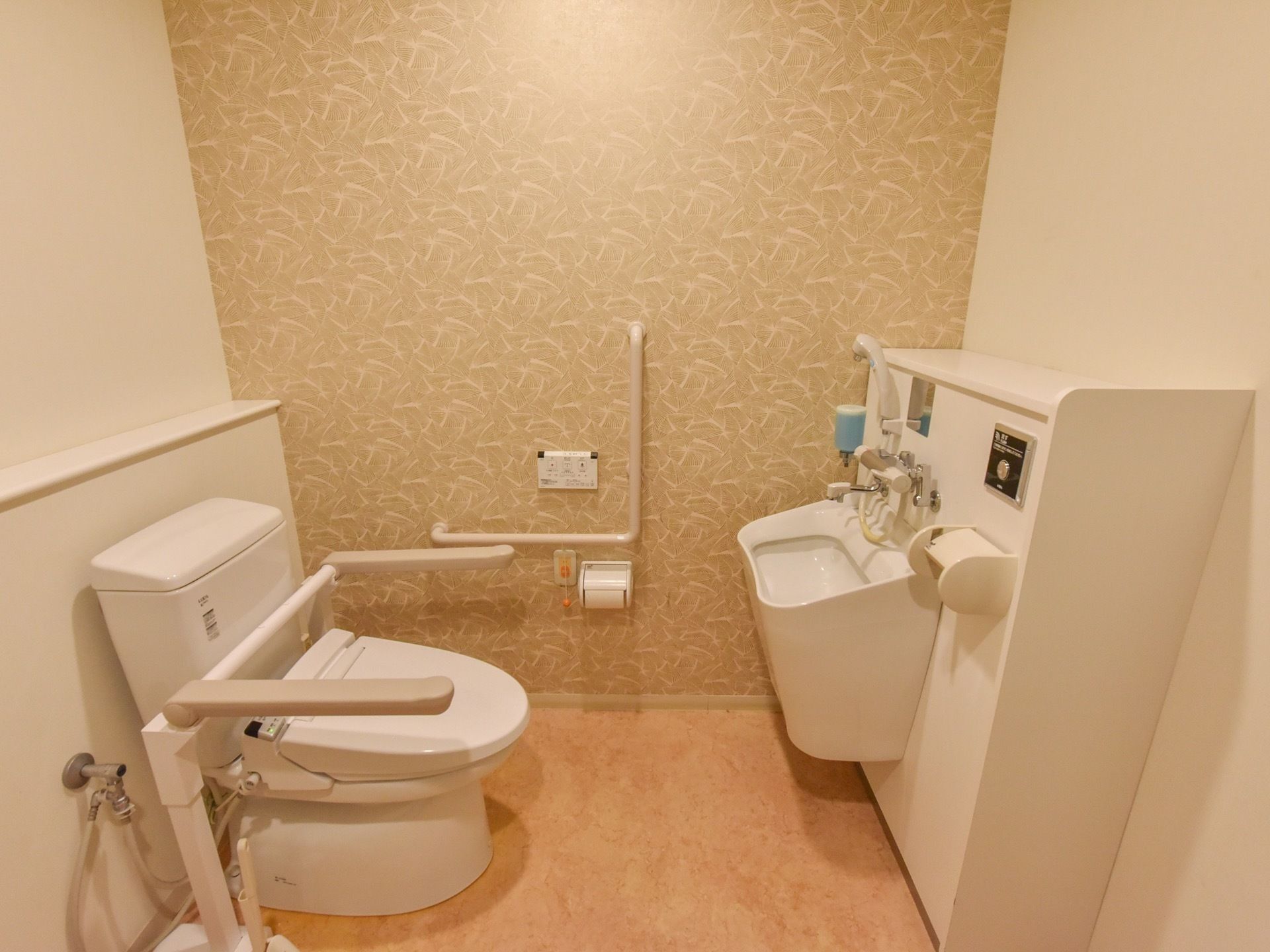 トイレの壁は、ベージュと白のツートンカラーでデザインされている。正面の壁にはＬ字型の手すりがあり、その下に呼出ボタンがある。