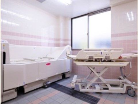 介助スタッフが数名入室してもゆとりの広さがある室内に、寝たままの姿勢で入浴できる介護入浴機器が置かれている。