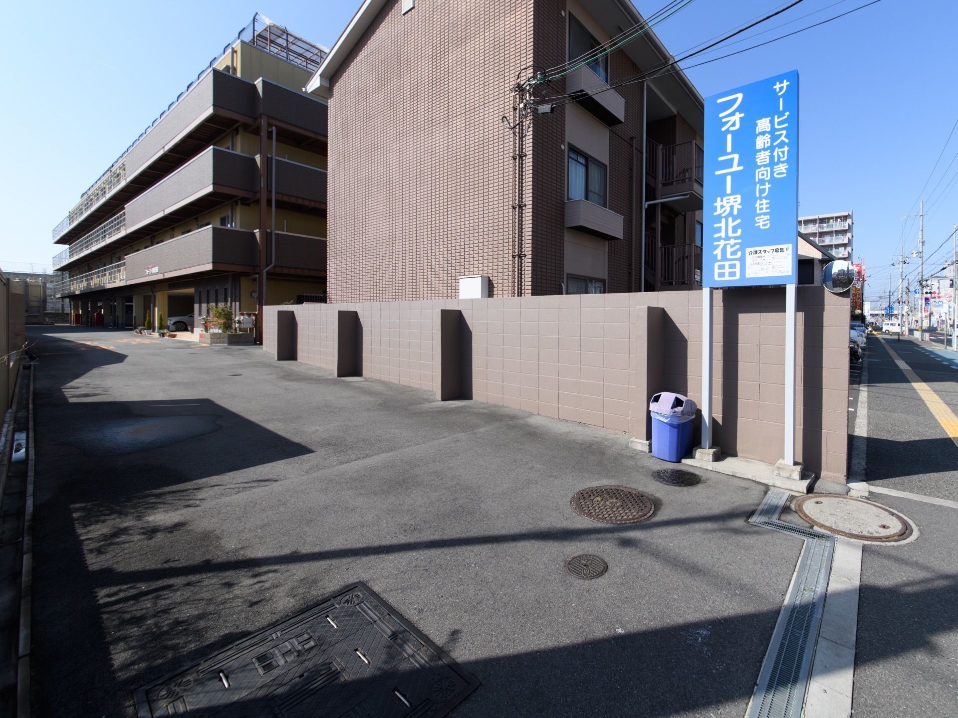 隣接する道路と敷地は、段差の少ない設計となっている。また前の歩道も広く、視覚障害者誘導用ブロックが備え付けられている。