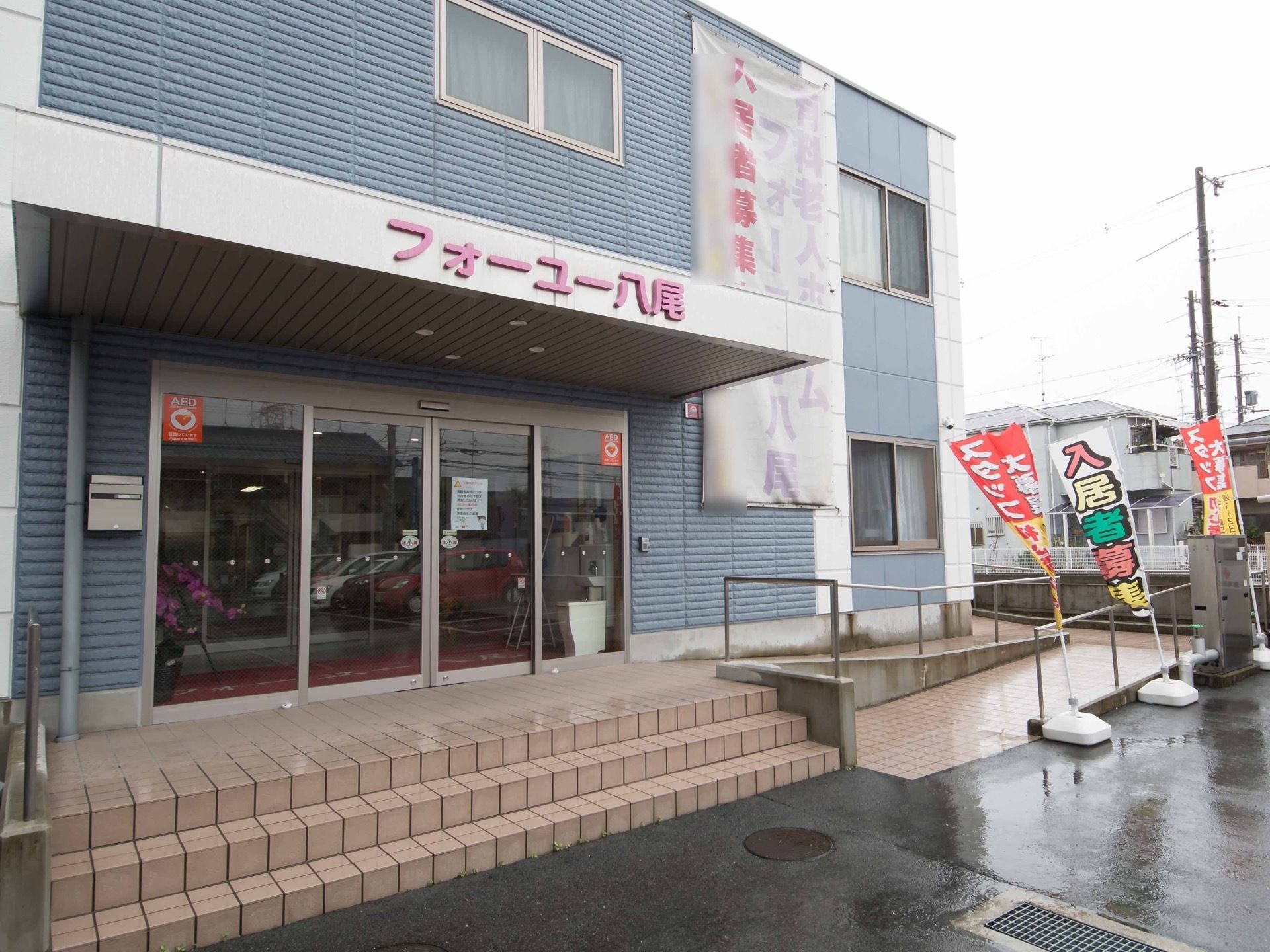 青い外壁の２階建ての建物である。玄関の扉はガラス張りの自動ドアになっており、安全に出入りすることができる。