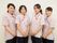 女性スタッフ４人の写真。ボーダーの半袖シャツと黒いパンツの制服を着用しており、赤い紐が付いたスタッフ証を首から掛けている。