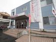 青を基調とした２階建てのグループホームである。入口はガラス張りの自動ドアで、前に手すりが設置されたスロープや階段がある。