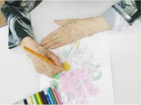 色鉛筆を持ち、花のデザインの塗り絵を楽しんでいる入居者様