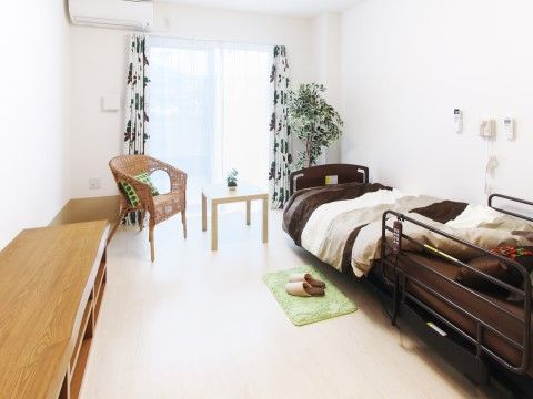リモコンで操作可能な介護ベッドが置かれているワンルーム
