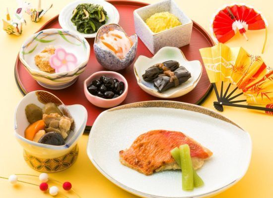 扇子や折り鶴が飾られたおせち料理