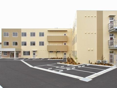 広い駐車場を完備している、３階建てのグループホーム