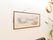 廊下の壁に複数飾られている絵画の内の１つの写真。水墨画風に高野山の絵が描かれている。廊下には観葉植物も置かれている。