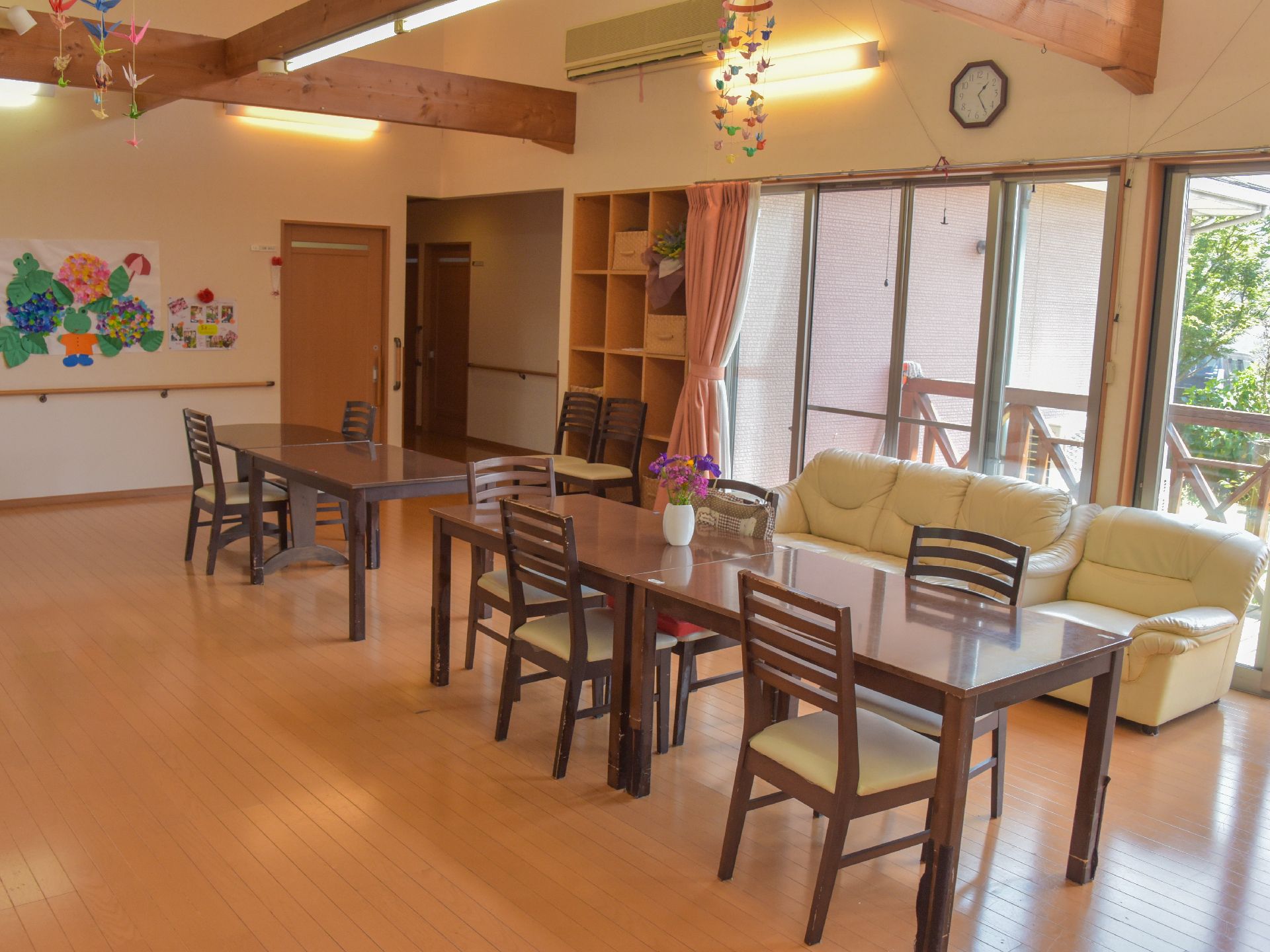 施設のリビングは廊下と繋がっているホールになっている。壁には手すりと入居者が製作した絵や飾りなどが飾り付けられている。