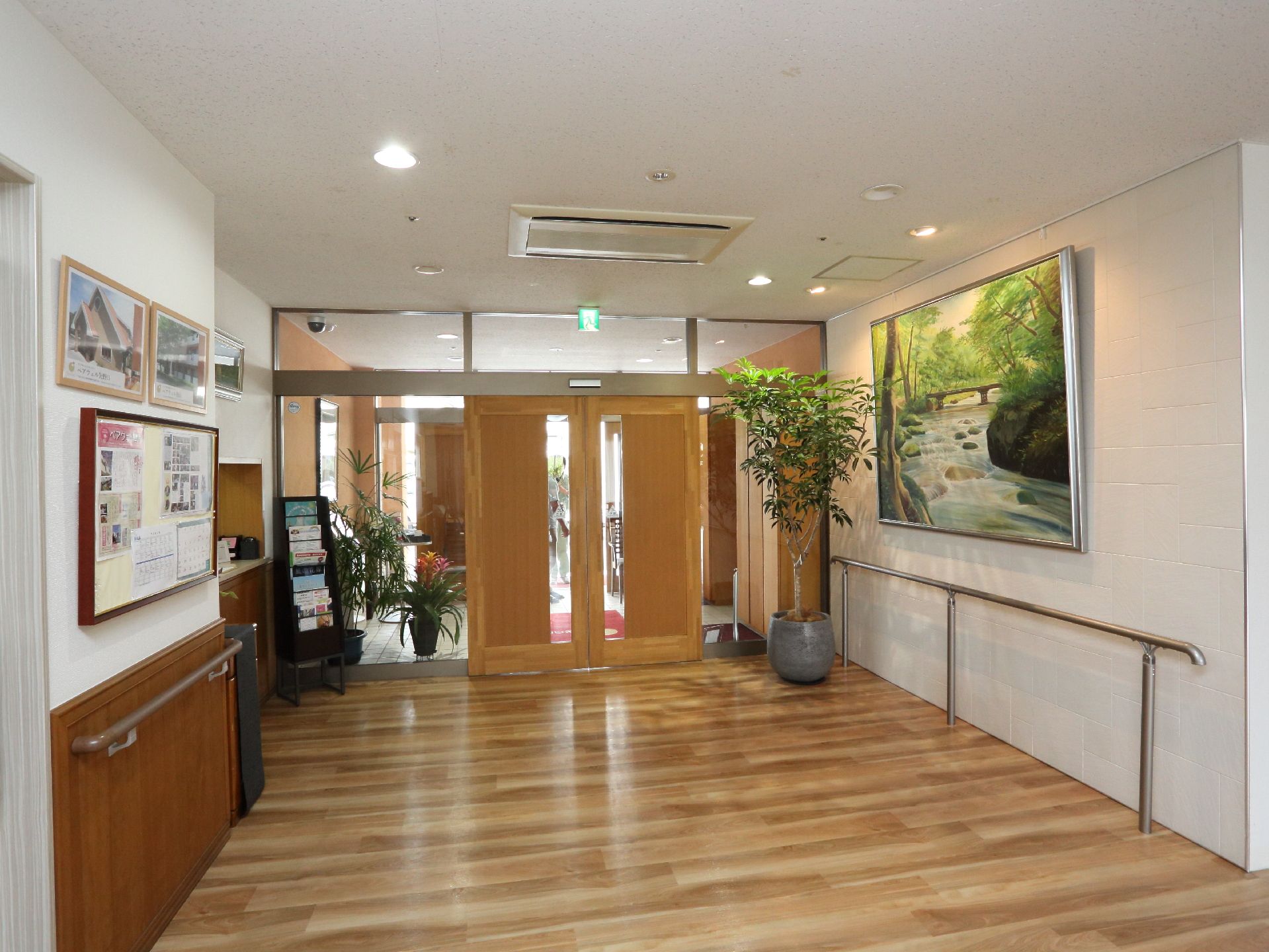 施設のエントランスは広く、壁には手すりがあり観葉植物や絵画が飾られている。窓口や資料が置かれていて掲示板も設置されている。