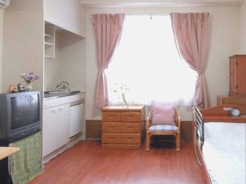 テレビやベッド、たんすなどの家具が置かれたワンルームの部屋
