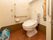 清潔感のある白壁のトイレの様子である。手すりを複数個所に設けているので、移動や立ち座りの際にご利用いただける。