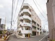 柔らかい色調の５階建て施設の外観である。住宅地に建っており、お車ではもちろんのこと、公共交通でも来訪していただきやすい場所である。