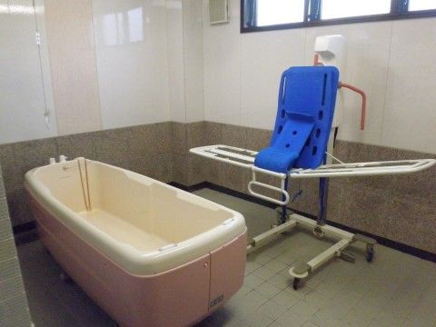 介護用の多機能な浴槽と入浴用のストレッチャーが置かれた浴室