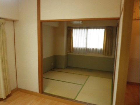 窓に黄色のカーテンがかかっており、奥の和室の部屋がある居室