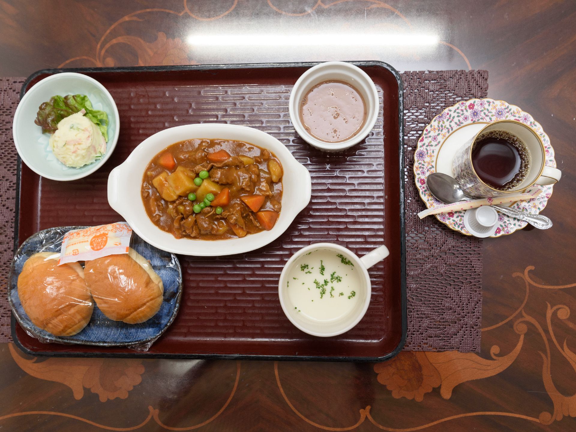 ロールパン２つ、野菜カレー、スープ、ポテトサラダのメニューとなっている。栄養バランスが考えられた献立である。
