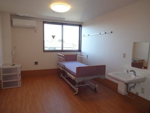 介護用リクライニングベッドと洗面所のある窓のある個室