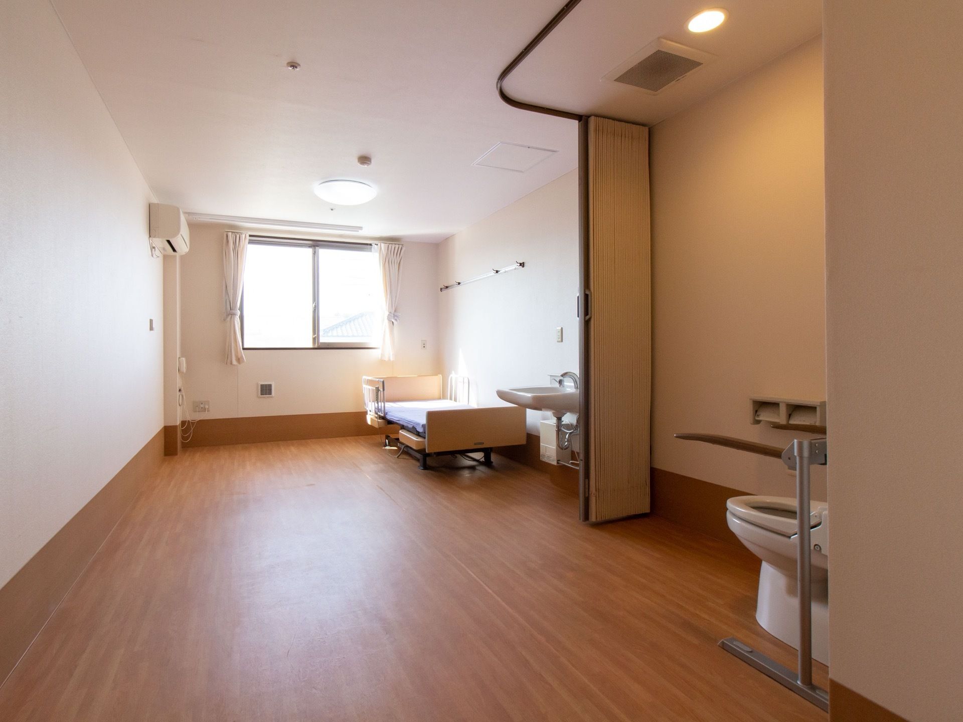 居室はフローリング張りの洋室である。トイレと居間はアコーディオンカーテンで区切られている。洗面台がある。