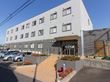 道路の面より一段高い敷地に建っている施設である。外壁は、１階部分が灰色、２階と３階部分が白色である。
